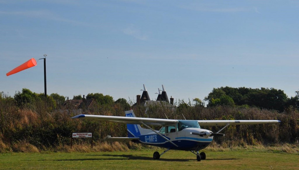 Farm Strips Fly Out Event - Safely parked up with coast houses in the distance. Don't like the look of that windsock much....